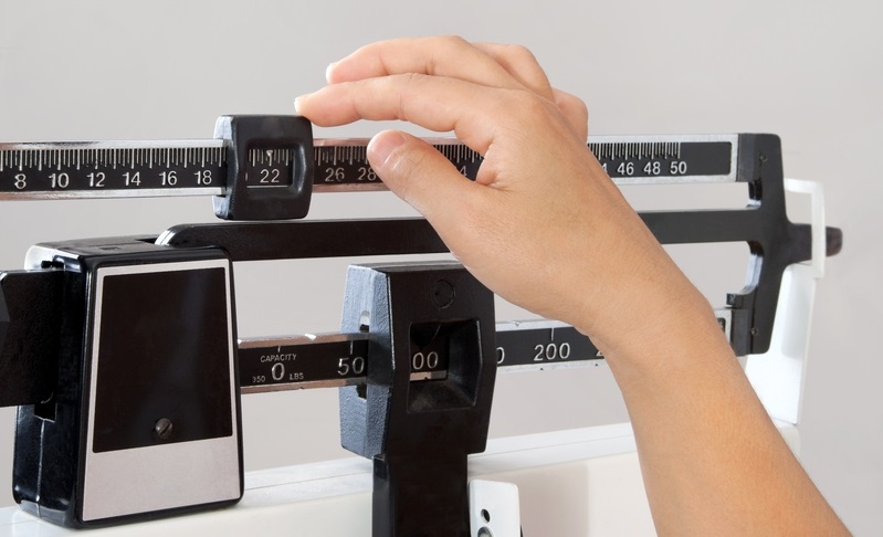 White hand adjusting scale cut weight