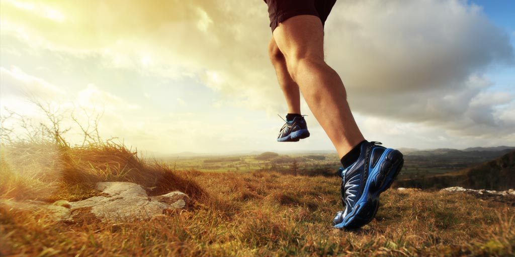 legs of runner outdoors with black and blue shoes