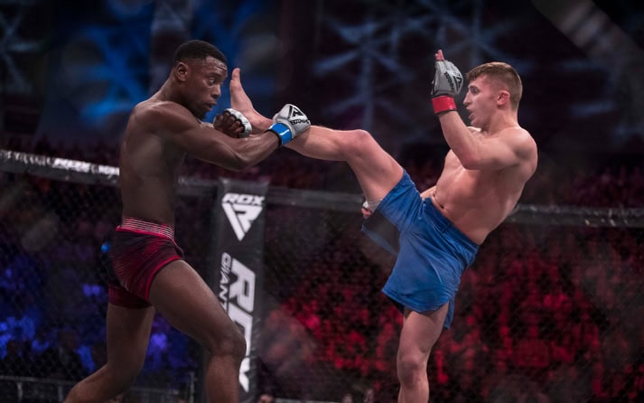 a person with blur trunka kicking the red trunks men with a leg kick and the red one stops the leg kick by blocking it